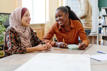 Two young women having chatting about something during lesson.