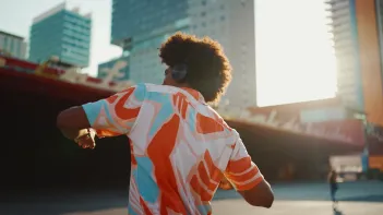 Man listening to music in headphones and dancing on urban city background.