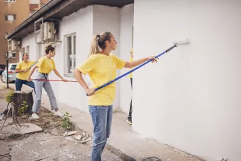 Volunteers painting building wall.