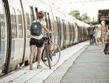 Young woman walking with bike on subway platform.