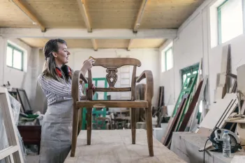 Female carpenter renovating an of old piece of furniture.