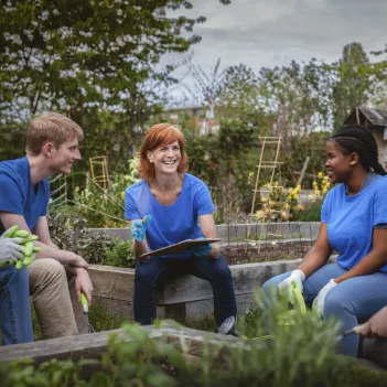 Female leader talks with group of younth volunteers gathered in community garden.