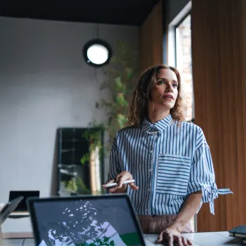 A woman holding a pen while talking to her colleagues and explaining something.