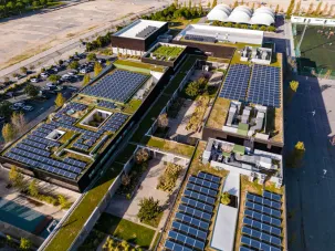 Overhead aerial rising view of a residential area and apartment block with solar panels installed on the rooftops