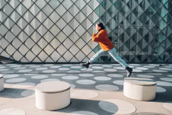 Girl jumping on asphalt town square with white dots in Berlin.