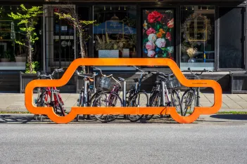 Front view of a bike rack with an orange facade in the shape of a car silhouette in Malmö, Sweden.