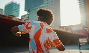 Man listening to music in headphones and dancing on urban city background.