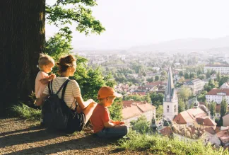 Woman with two little children looks at panorama of european city from a hill. 