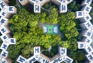 Queens bridge Houses basketball court surrounded by trees and rooftops from the sky