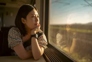 Young female traveling by train, looking out the window.