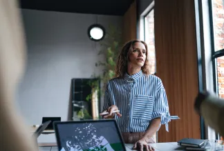 A woman holding a pen while talking to her colleagues and explaining something.