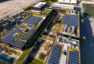 Overhead aerial rising view of a residential area and apartment block with solar panels installed on the rooftops