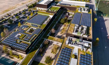 Overhead aerial rising view of a residential area and apartment block with solar panels installed on the rooftops