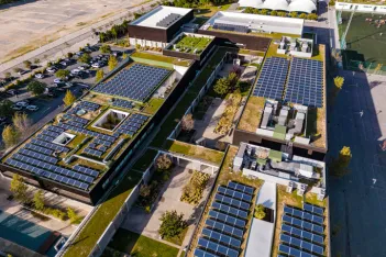 Overhead aerial rising view of a residential area and apartment block with solar panels installed on the rooftops