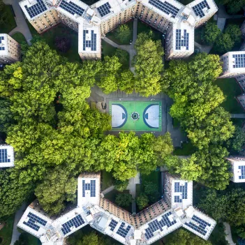 Queens bridge Houses basketball court surrounded by trees and rooftops from the sky