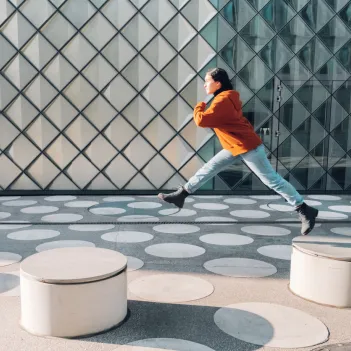 Girl jumping on asphalt town square with white dots in Berlin.