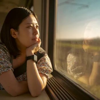 Young female traveling by train, looking out the window.