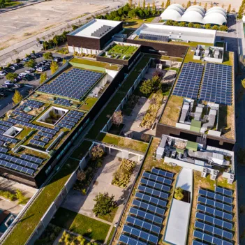 Overhead aerial rising view of a residential area and apartment block with solar panels installed on the rooftops